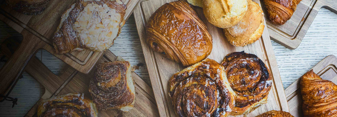 An assortment of pastries on wooden boards, including croissants and cinnamon rolls.