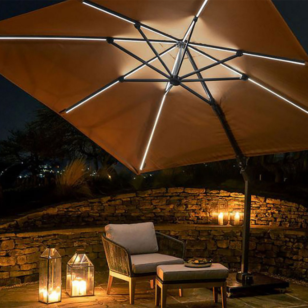 Cozy outdoor seating area with a lit umbrella, candles, lanterns, and a small table on a wooden deck.'