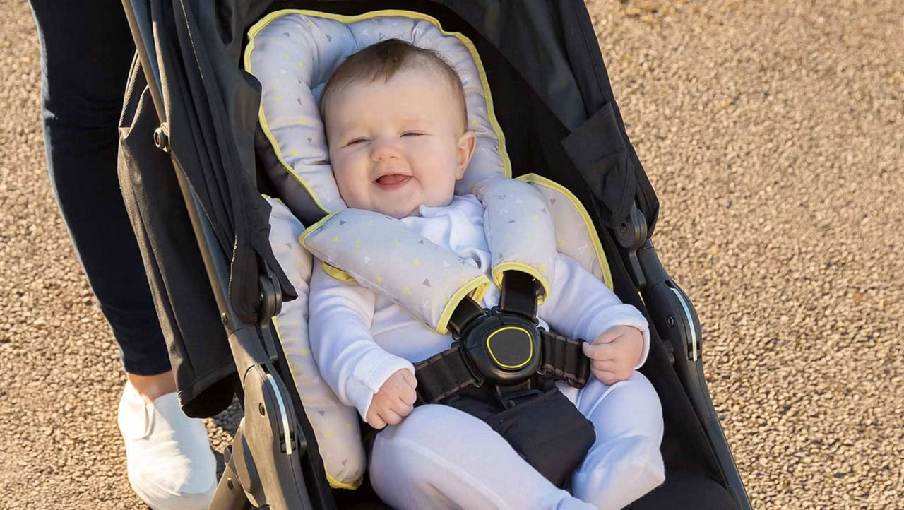 A baby wearing a white babygrow strapped into a black boogie.