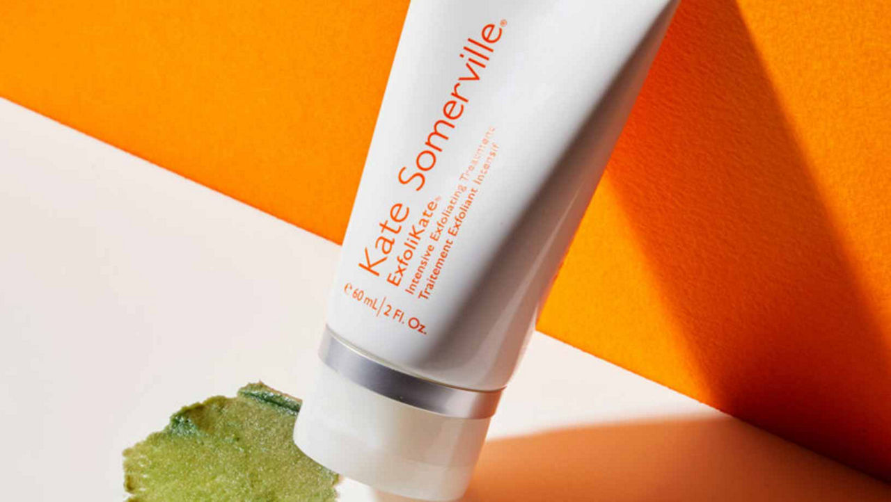 Kate Somerville ExfoliKate product on a white and orange background with green product swatched to the left