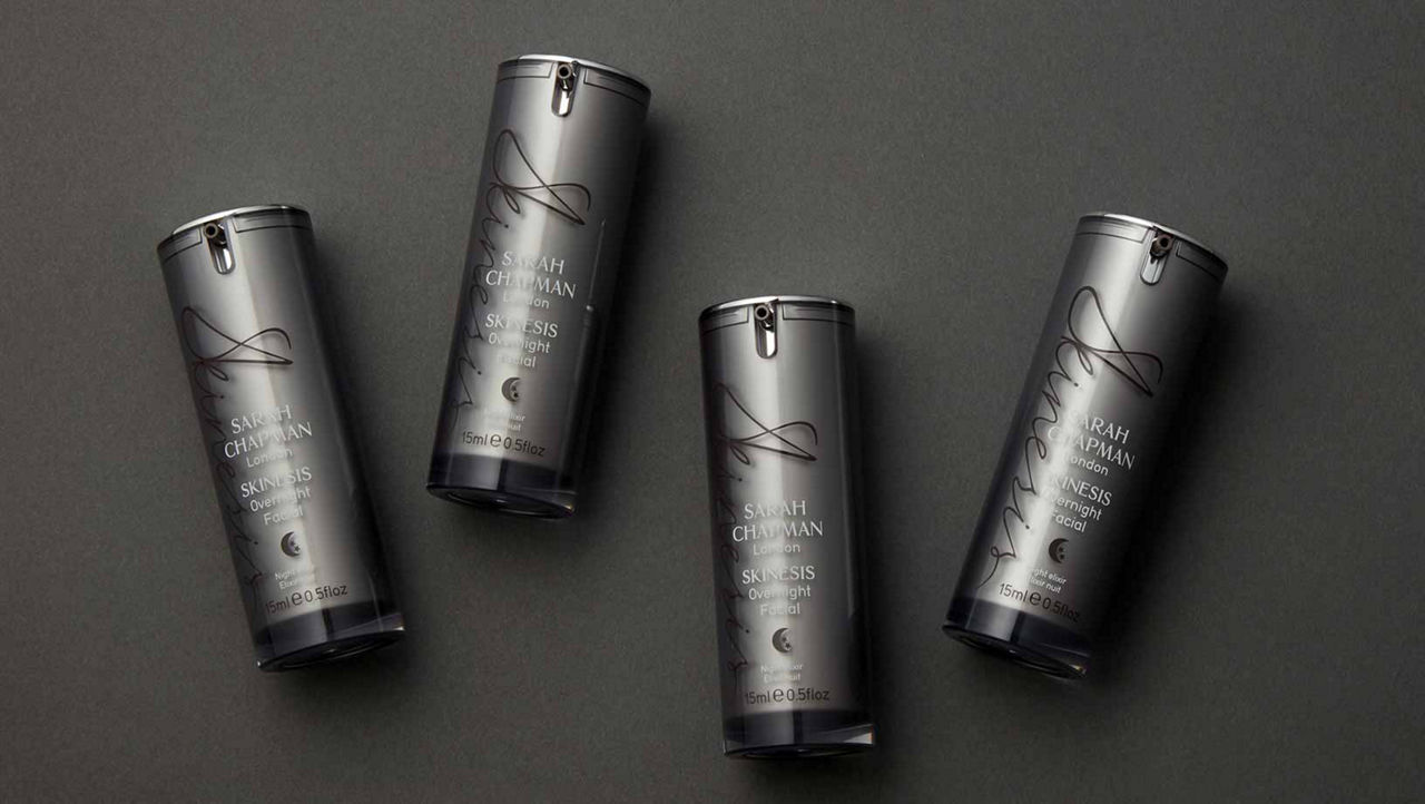Four Sarah Chapman Overnight Body Treatment products shot on a dark gray paper background