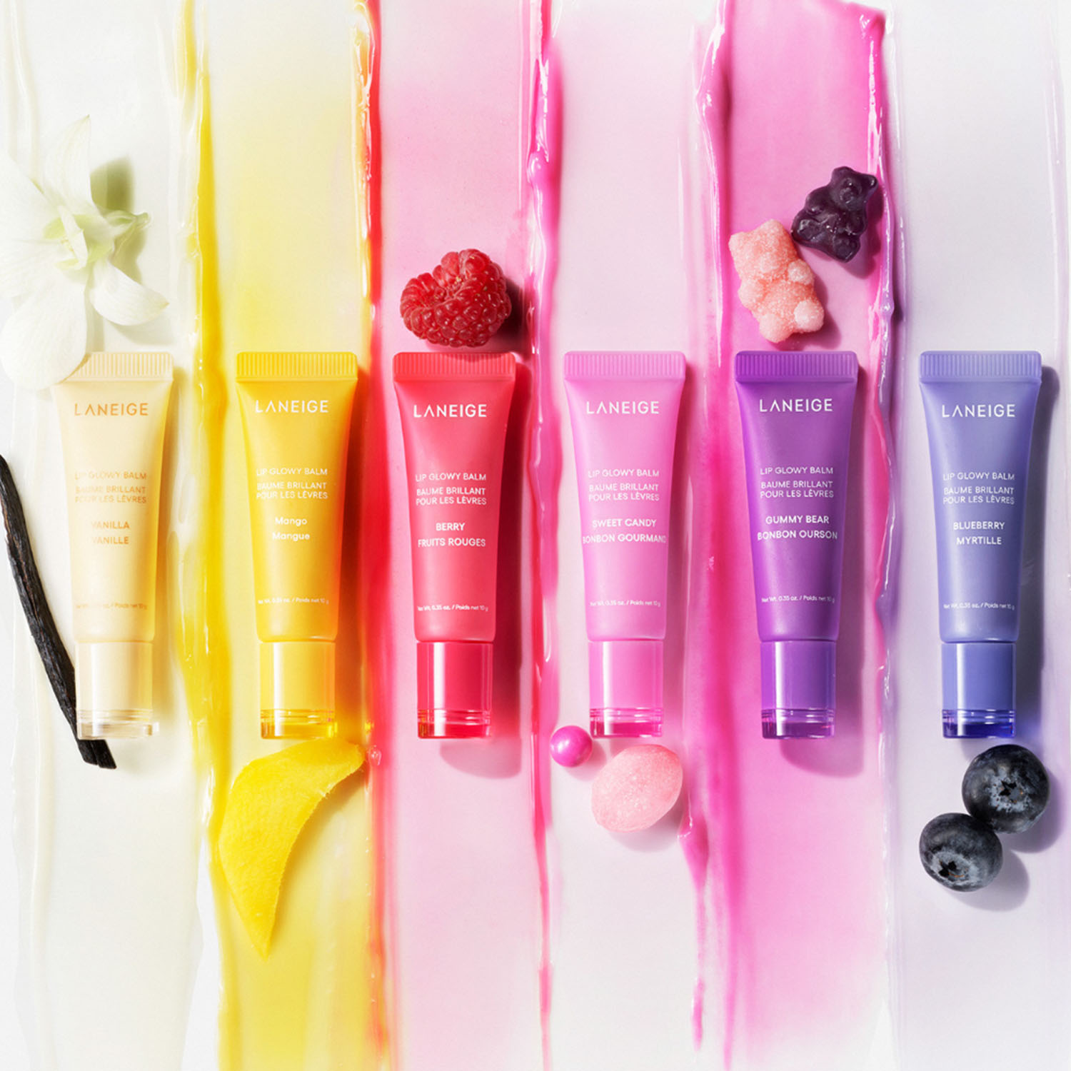 Colorful lip gloss tubes arranged with matching fruit and textures.