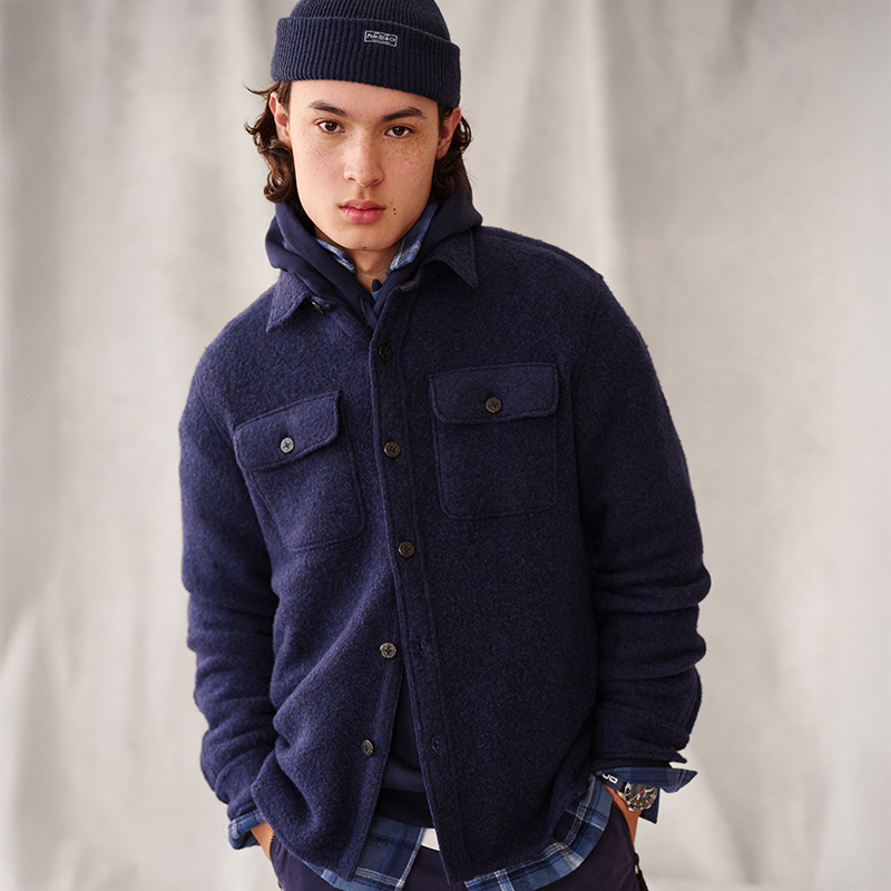 Person wearing a navy jacket and beanie, standing against a light background.