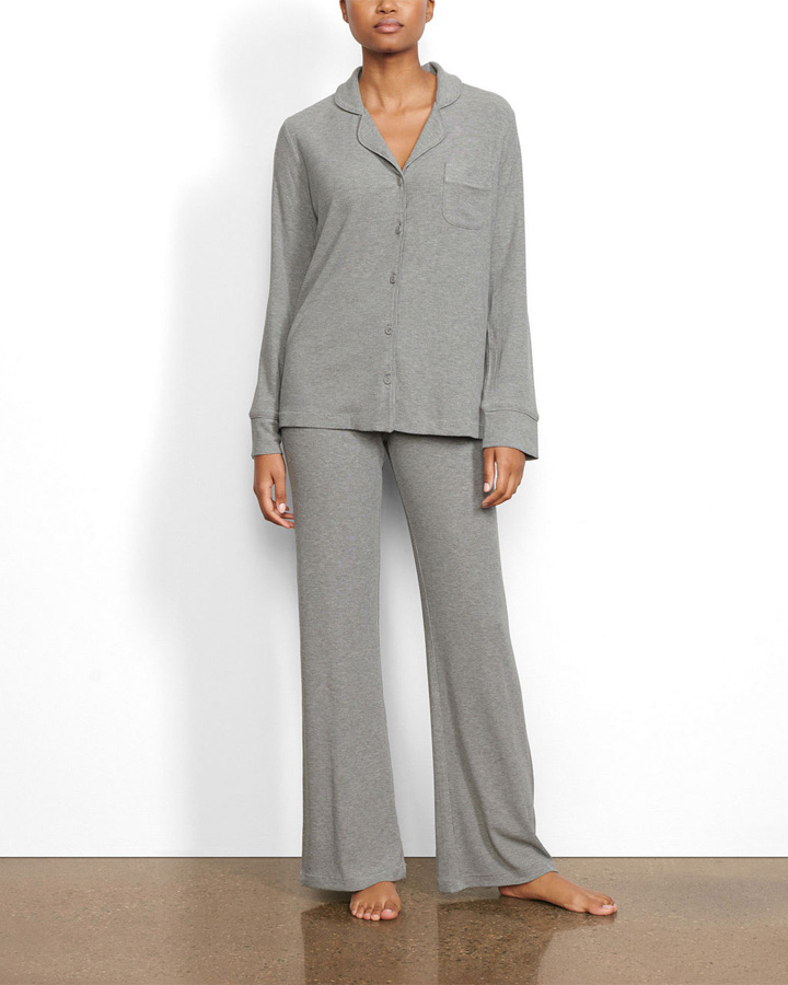 Person wearing a gray pajama set, featuring a long-sleeve top with buttons and matching pants, standing barefoot.
            style=