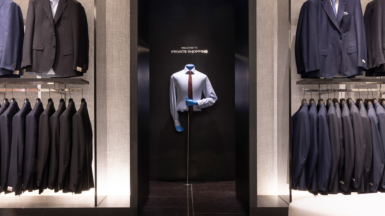 A clothing store display with suits and a central mannequin dressed in a blue shirt and red tie, labeled 'Private Shopping.'